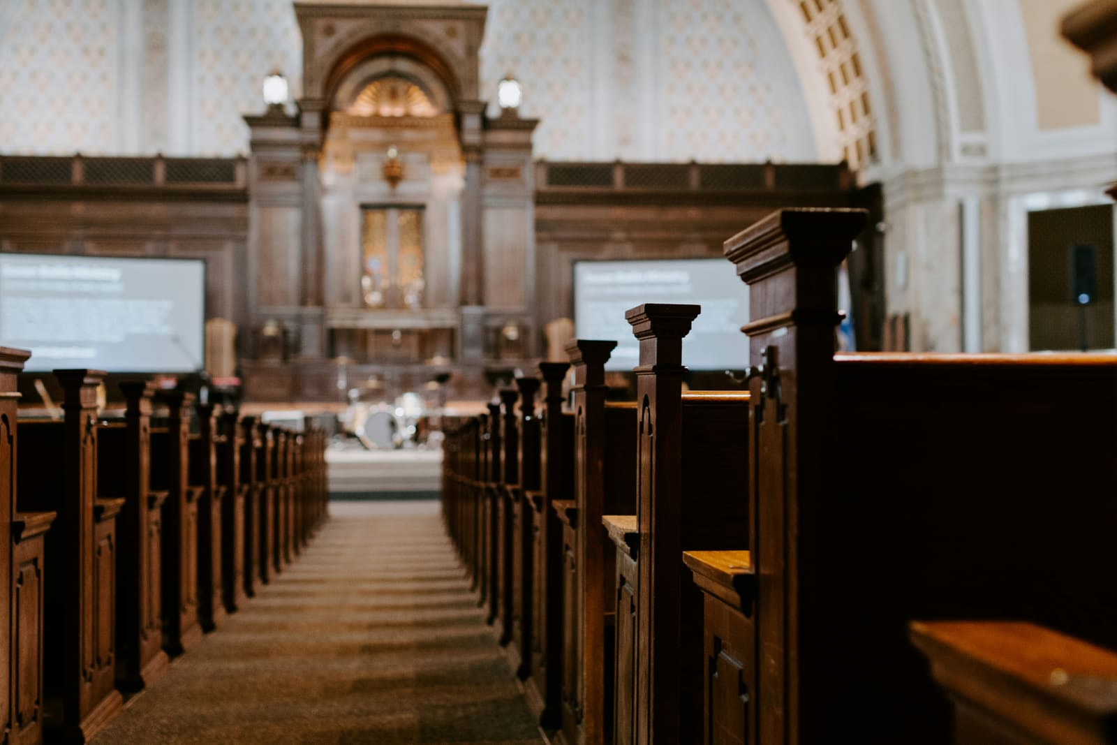 The interior of an ordinary church, empty pews leading to the altar, in daylight.