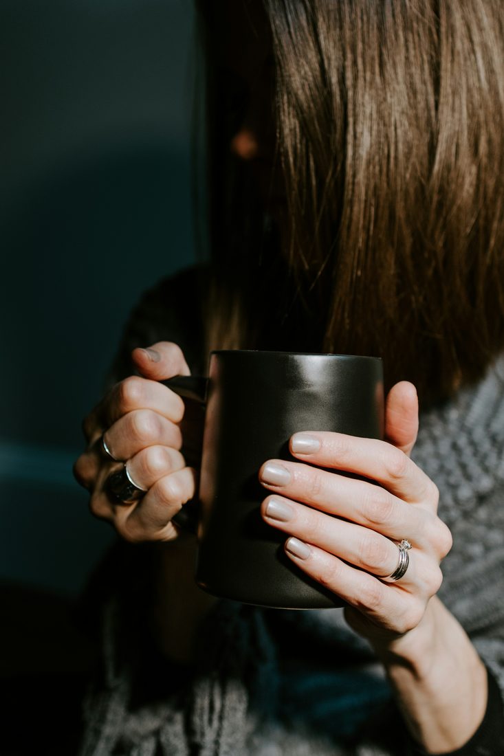 Hands wrapped around a dark mug of coffee
