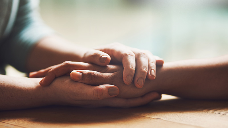 Close-up of hands holding each other, symbolizing generosity, support, and donations helping sustain the mission.