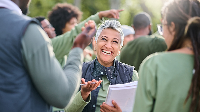 A cheerful volunteer engaging with a group, representing community members supporting seniors in staying active.